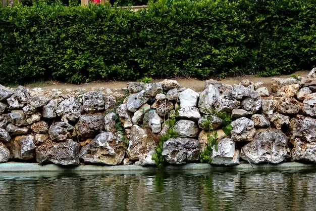 Dry-laid stone retaining wall beside water, the kind of wall a condition review examines